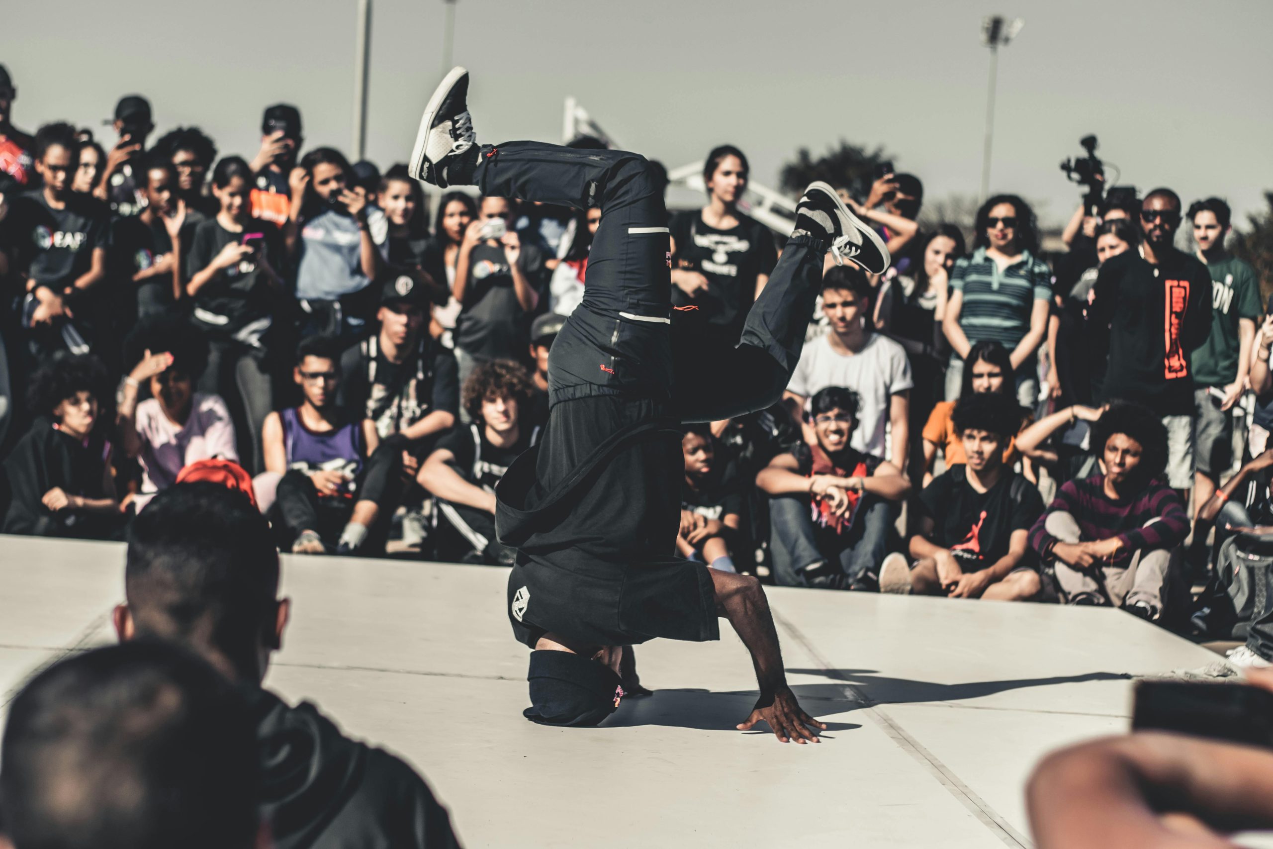 Outdoor breakdance event with diverse crowd enjoying a lively street performance.